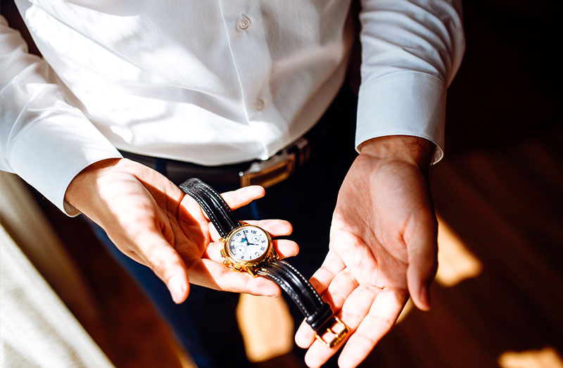Orologio elegante con cinturino in pelle Watches and More_Persona tiene tra le mani un orologio da polso elegante con cinturino in pelle nera.